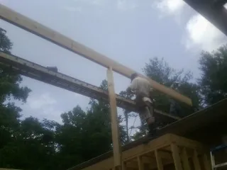 Carpenter setting a ridge beam over a new addition frame — Ice Dam Removal by Roofing Brothers in Bloomington Springs