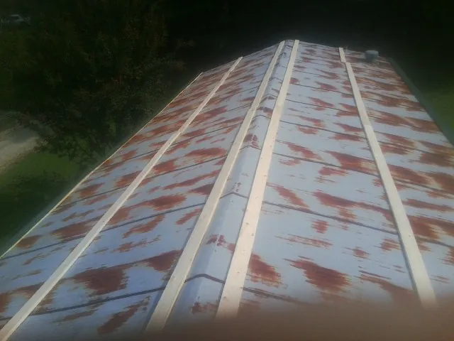 Rusted metal roof panels with new wood purlins before replacement — Storm Damage Roof Repair in Bloomington Springs by Roofing Brothers