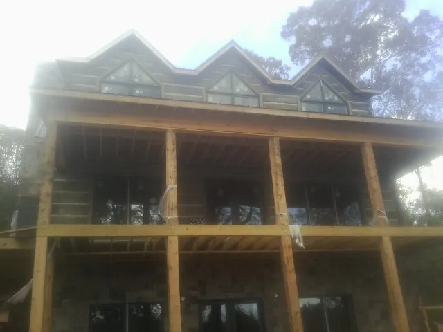 Dormers and porch framing on a large log home under construction — Roof Coating work by our crew in Bloomington Springs