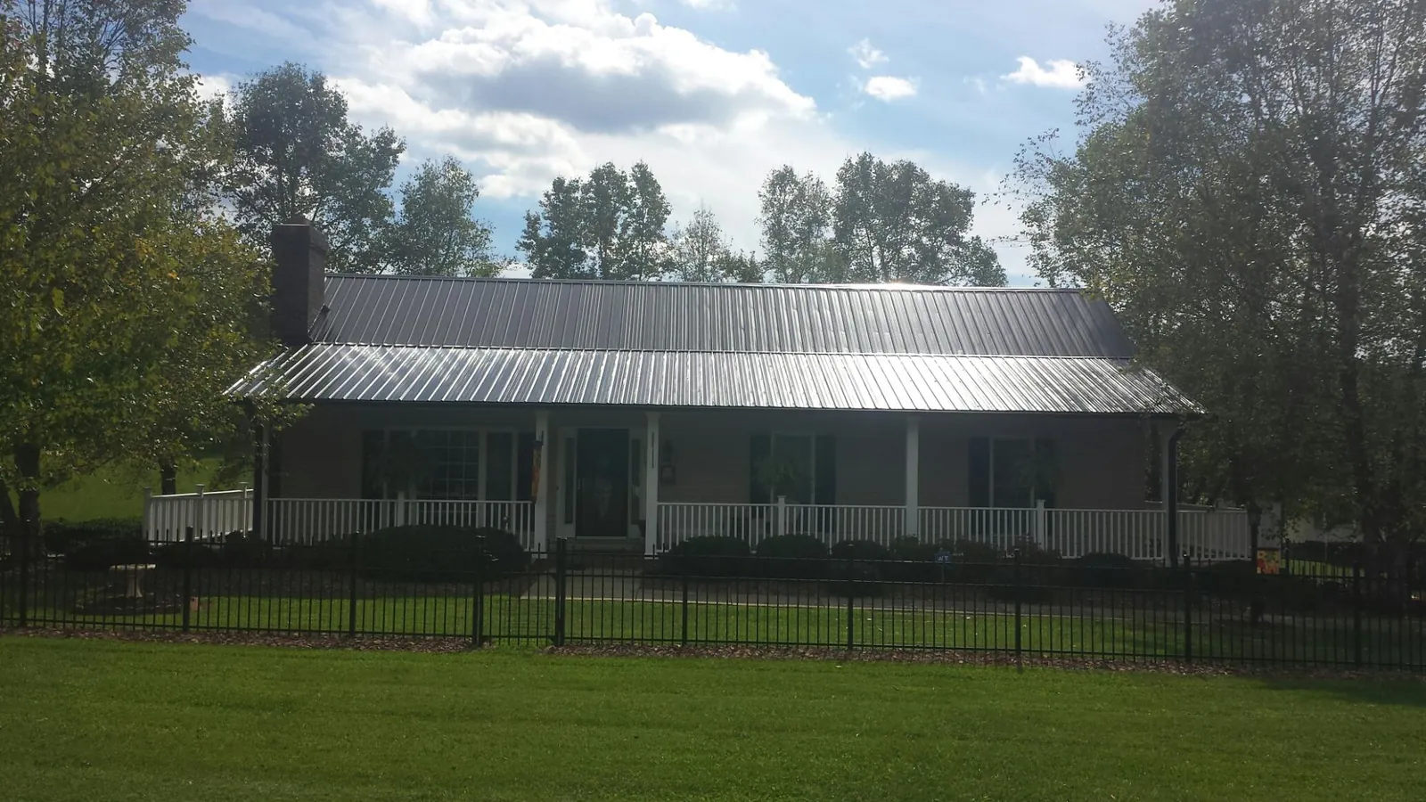 Gray metal roof on a brick ranch with a full width front porch — Gutter Guard Installation work by our crew in Bloomington Springs