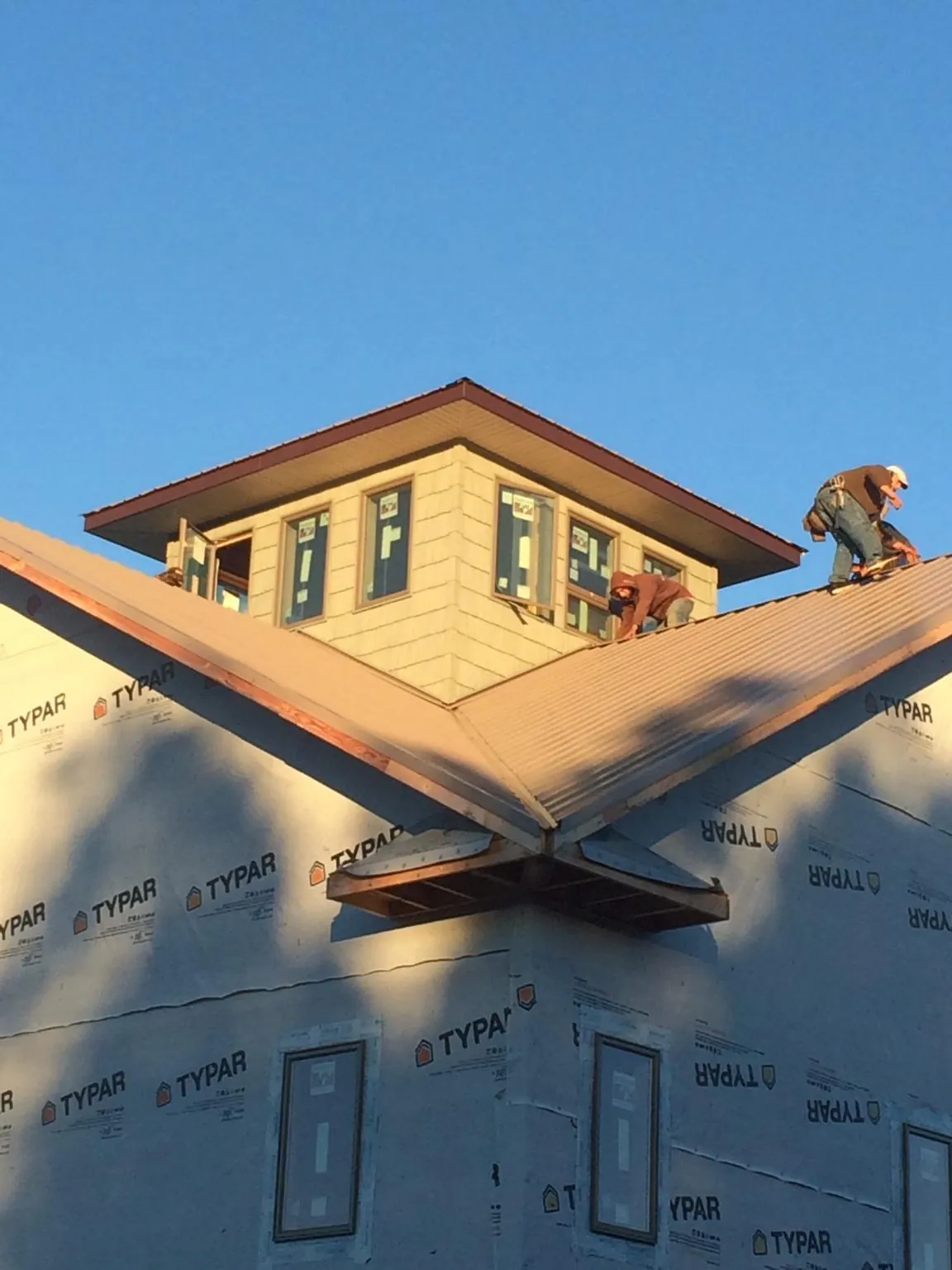 Roofers working around a rooftop cupola on a new metal roof at sunset — Roof Waterproofing in Bloomington Springs by Roofing Brothers